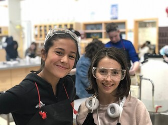 two female students posing together in a classroom